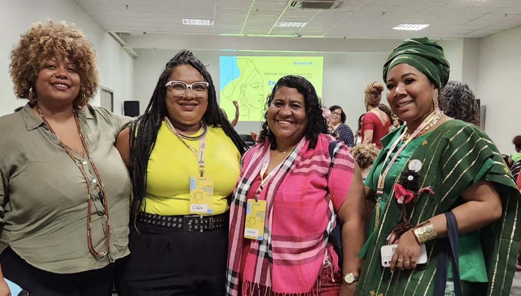 Four women smiling together at a meeting hosted by CONAQ. 