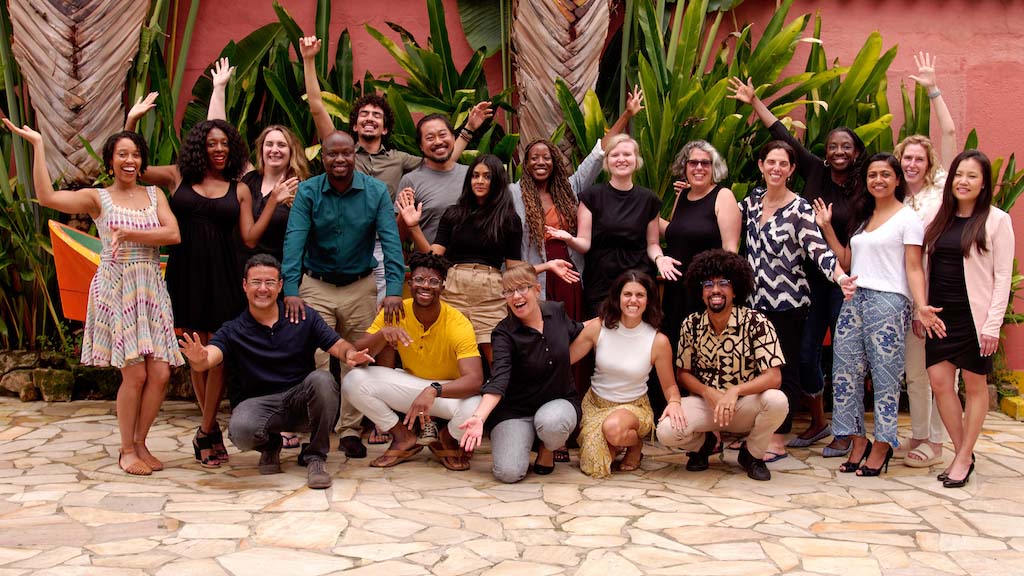 A group of twenty people looking up and waving.